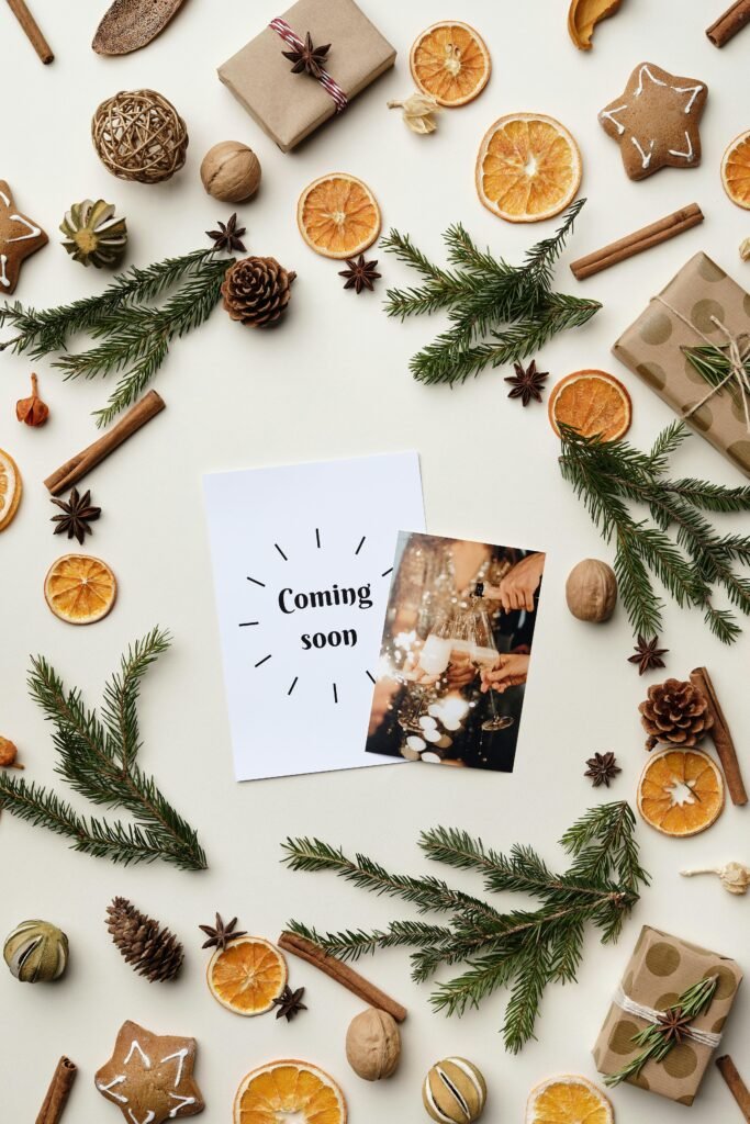 Flat lay of holiday decorations with dried oranges, spices, and conifer sprigs.